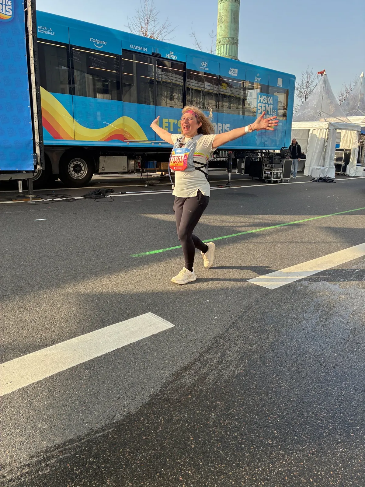 Une participante du programme franchit la ligne d'arrivée du Semi de Paris, bras ouverts